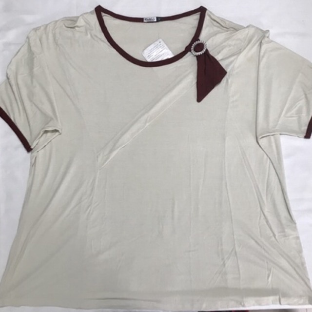 Camiseta adulto feminino Rodher Fashion Modelo com costura sobreposta discreta na diagonal Detalhe com fivela na gola Tecido leve e confortável Cor bege com detalhes vermelho terra Tamanho XL Marca Rodher Fashion Composição: 95% Viscose e 5%Elastano