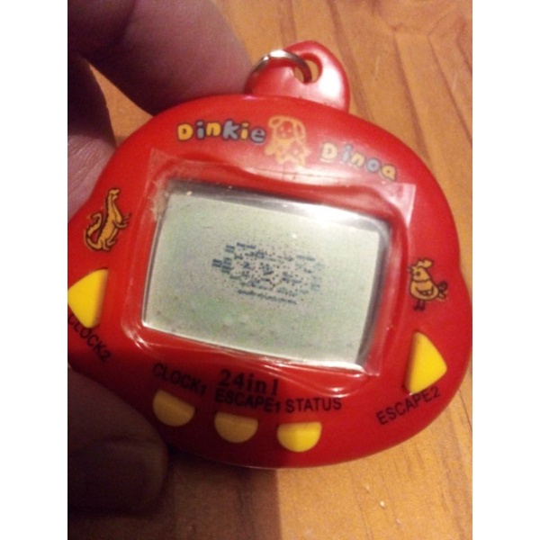 Bichinho virtual antigo Tamagotchi Dinkie Dino vermelho no blister