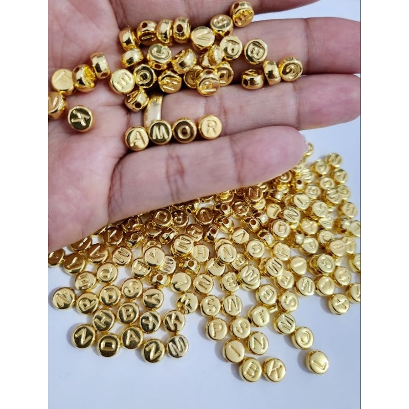 Miçangas Letras Dourada 4x7mm 300 Peças. em Oferta na Shopee