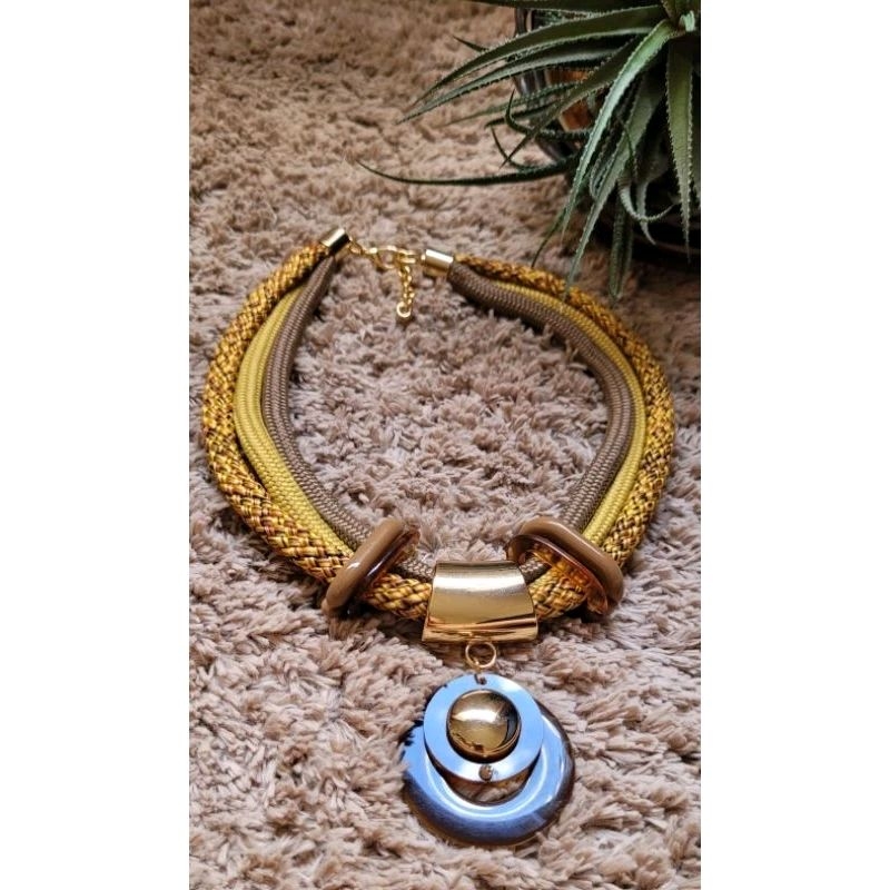 Maxi colar c/corda náutica mescla e fio amarelo mostarda e marrom claro c/ peça dourada folheada a ouro e pingente de resina marrom mel e dourado no centro c/stress mel.
