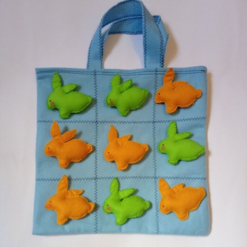 Jogo da velha páscoa, jogo pedagógico e educativo com peças de coelhos verdes e laranja, bolsa azul, dia das crianças