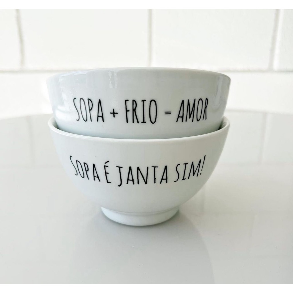 Dois bowls de porcelana branca empilhados, com frases em letras pretas: o de cima diz 'SOPA + FRIO = AMOR' e o de baixo 'SOPA É JANTA SIM!'