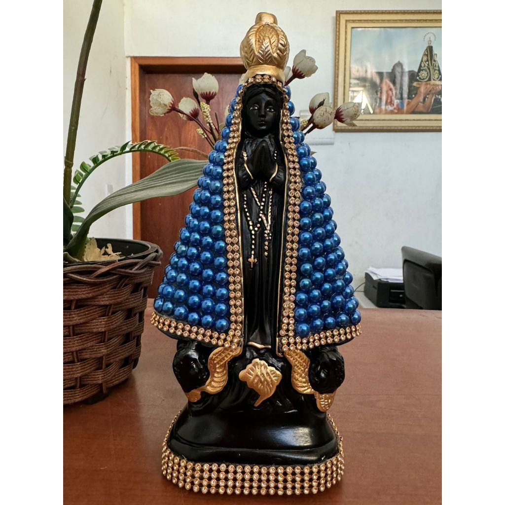 Imagem de Nossa Senhora Aparecida com o manto revestido de pérola bege e detalhada com strass dourado. Imagem pintada com branco pérola. Preço promocional.