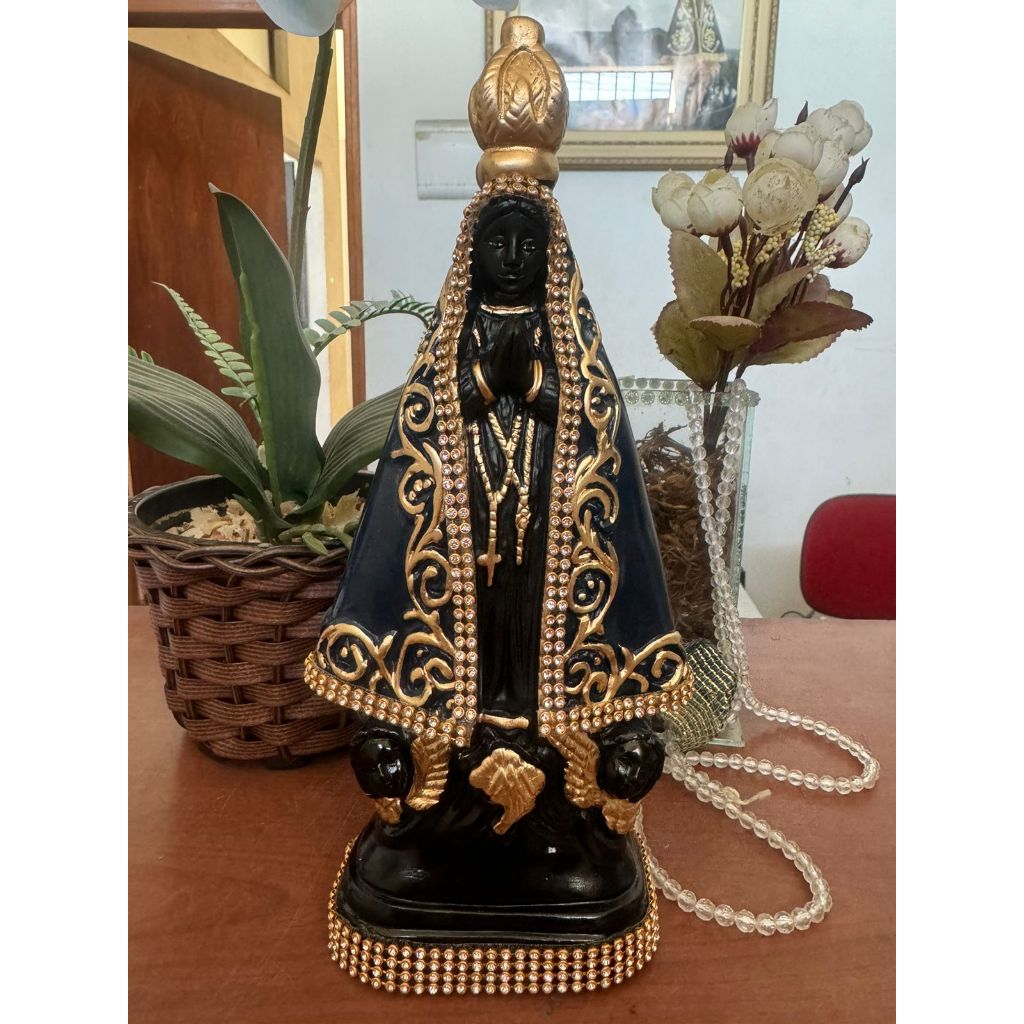 Imagem de Nossa Senhora Aparecida em 25cm detalhada com strass dourado. Feita com produtos de alta qualidade e pintada cm tinta automotiva, resistente ao desbotamento.