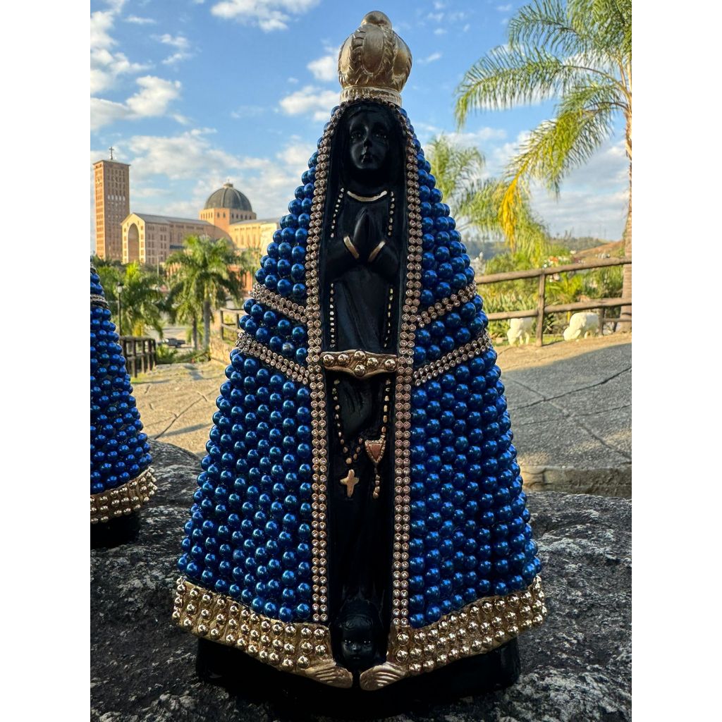 Imagem de Nossa Senhora Aparecida 30cm com pérola azul royal e dourada. Detalhadas com strass dourada e ricas em detalhes. Imagem da Mãe Aparecida nas cores preta e branco pérola na parte central. Pintadas com tinta automotiva, resistente ao desbotamento.
