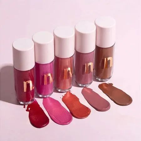 Cinco frascos de Blush Líquido Nina Makeup da linha Western em diferentes tons, com amostras de cor aplicadas na superfície abaixo de cada embalagem.