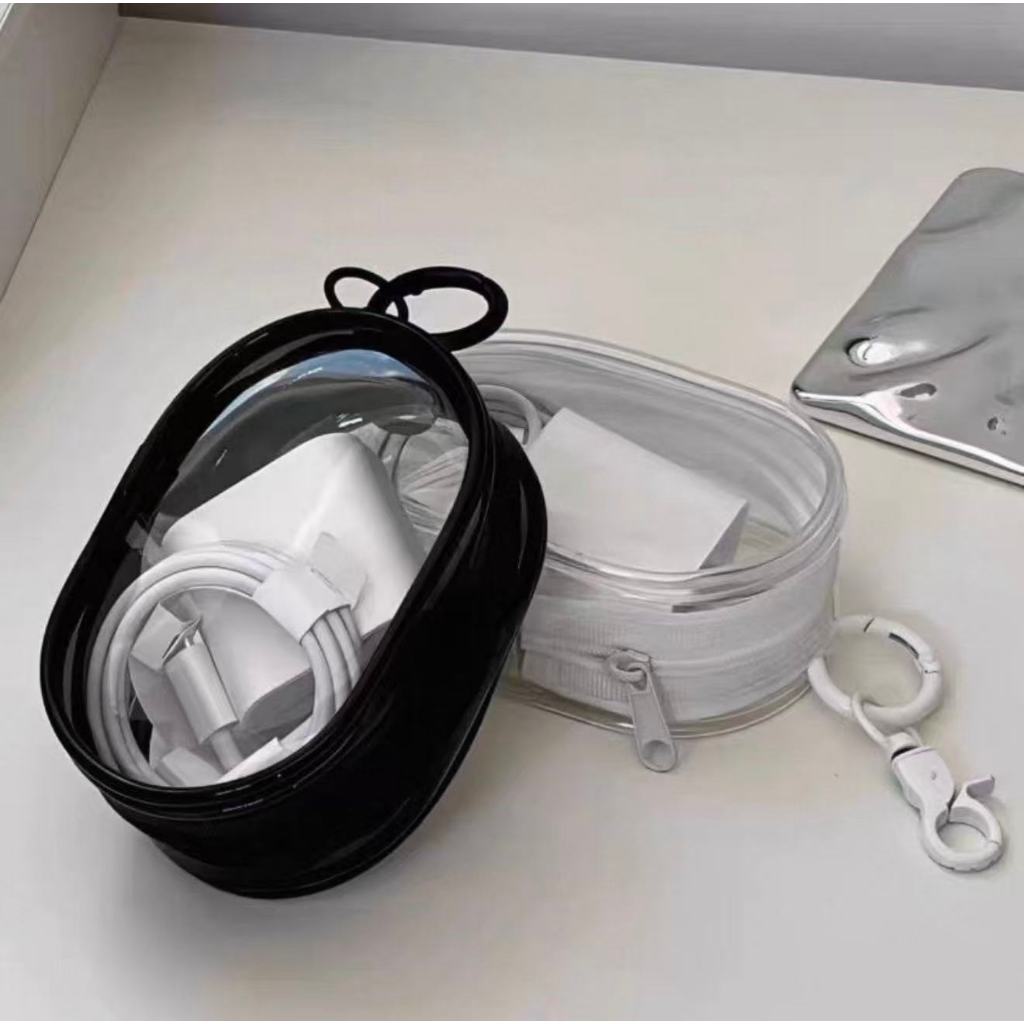 Duas bolsas organizadoras portáteis, uma preta e uma transparente, contendo carregadores e cabos de dados, com um gancho mosquetão ao lado.