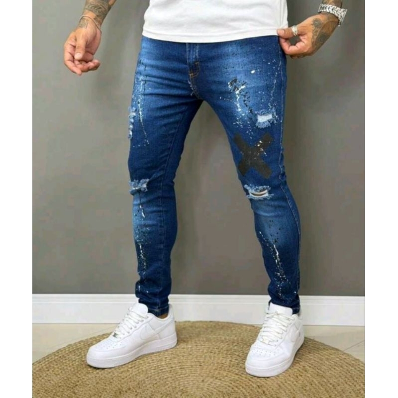 Calça jeans masculina de denim altamente elástico, rasgada, com estampa de respingos de tinta e bolsos.