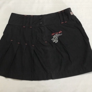 Minissaia Surfista Adulto Feminino  Modelo em tecido tactel, drapeado e com discreta estampa Cós largo, fecho em zíper e 2 botões Cor preto com costura discreto em laranja Tamanho 42 Marca Idio’s Composição: 81% Algodão e 19% Poliéster