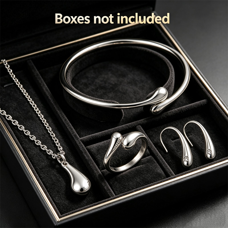 Conjunto de joias em formato de gota, composto por quatro peças em ouro ou prata: brincos, colar, pulseira e anel.