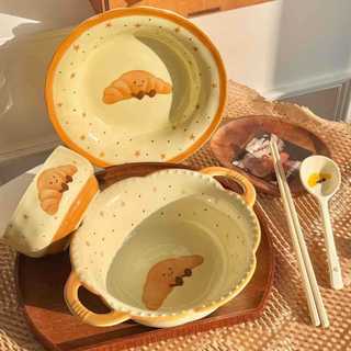 Conjunto de louça de cerâmica com motivos de croissant e frutas, em cores vibrantes, com design feminino. Inclui tigelas