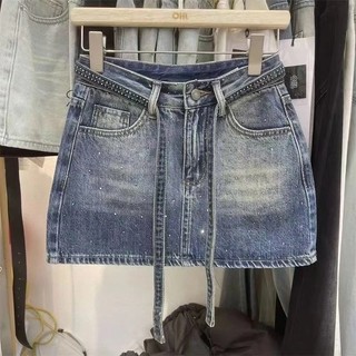 Coleção Verão 2026: Minissaia jeans de cintura alta, corte em A, com detalhes em strass, em blocos de cor, lavada, versá
