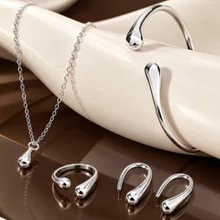 Conjunto de joias em formato de gota, composto por quatro peças em ouro ou prata: brincos, colar, pulseira e anel.